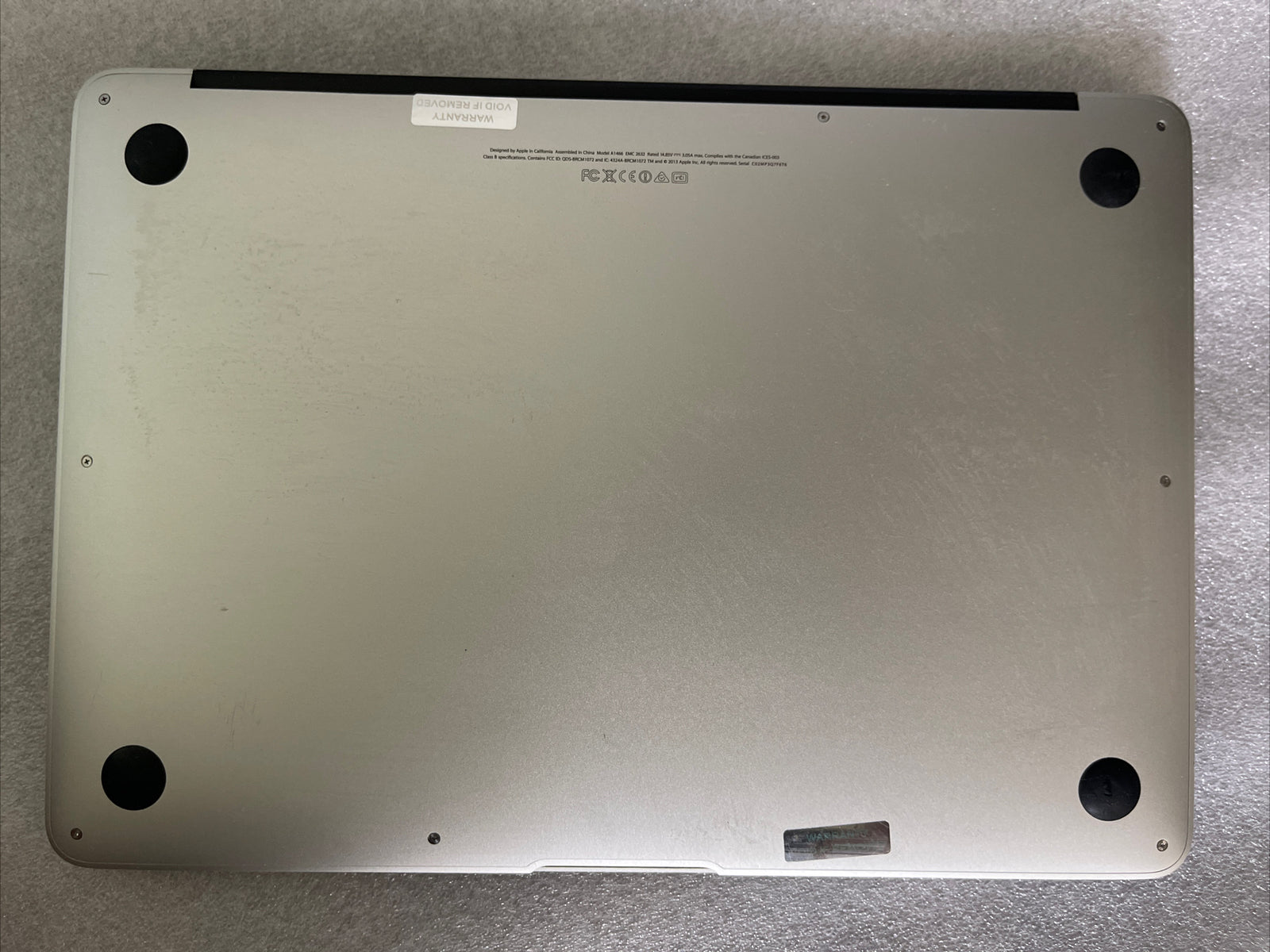 Silver Apple MacBook Air 13 inch bottom view showing screws and rubber feet, 2013 model with Intel Core i5 processor