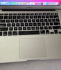 Silver Apple MacBook Air 13-inch with Intel Core i5 keyboard and trackpad showing partial screen and macOS Big Sur background