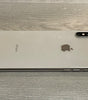 Silver Apple iPhone XS Max lying face down on wooden surface showing dual camera and side buttons