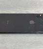 Black Apple iPhone XS Max with dual camera lying face down on a gray wooden surface showing its sleek design