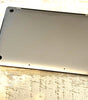 Apple MacBook Pro 15-inch bottom view showing Sequoia color aluminum case with rubber feet and screws visible