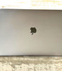 Space Gray Apple MacBook Pro 15-inch closed lid with Apple logo on rustic wooden surface, model A1990 with Touch Bar