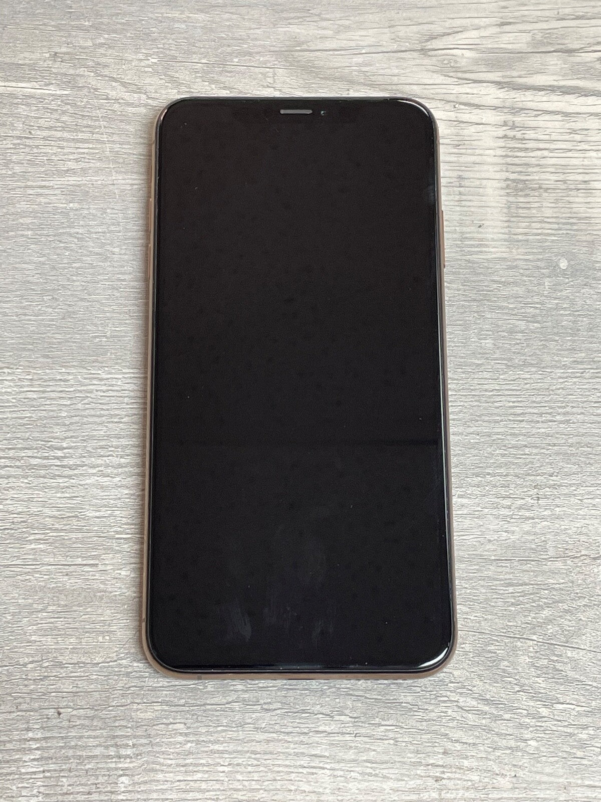 Apple iPhone XS Max with 6.5-inch screen and black display lying on a wooden surface, factory unlocked model A2101.