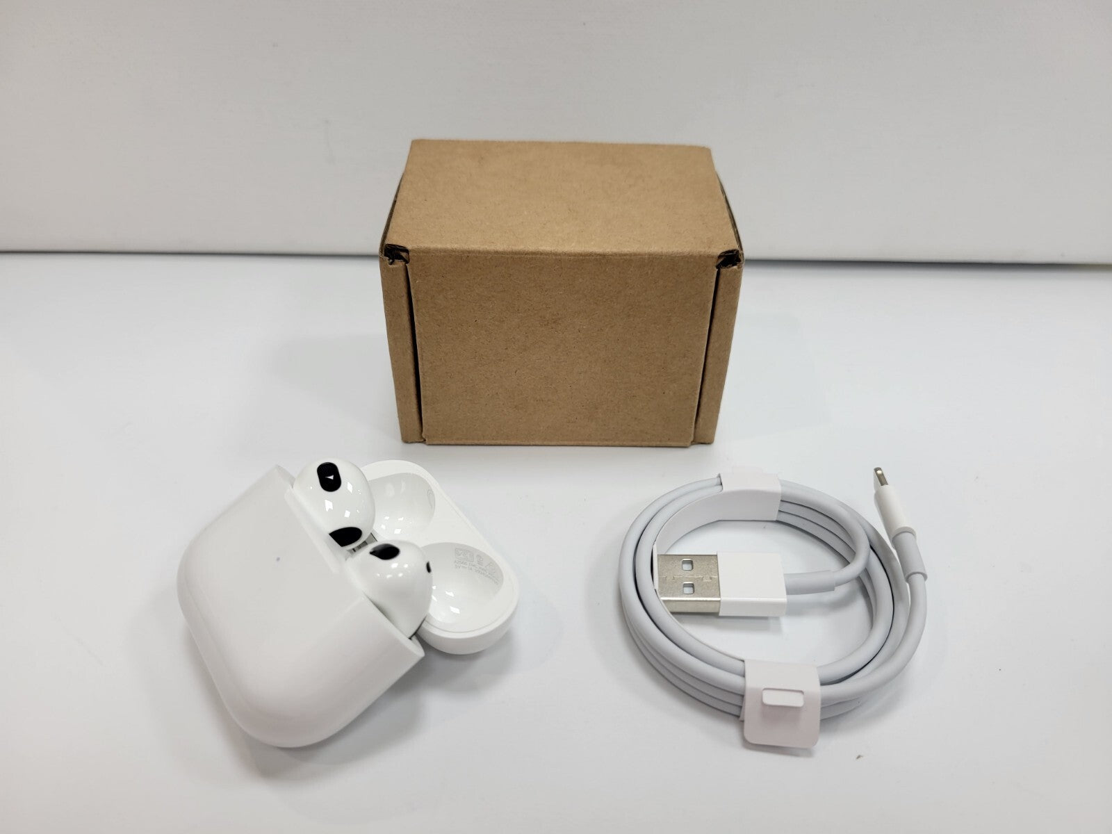 Apple AirPods 3rd Generation wireless white in-ear earbuds with charging case, USB charging cable, and plain brown box packaging