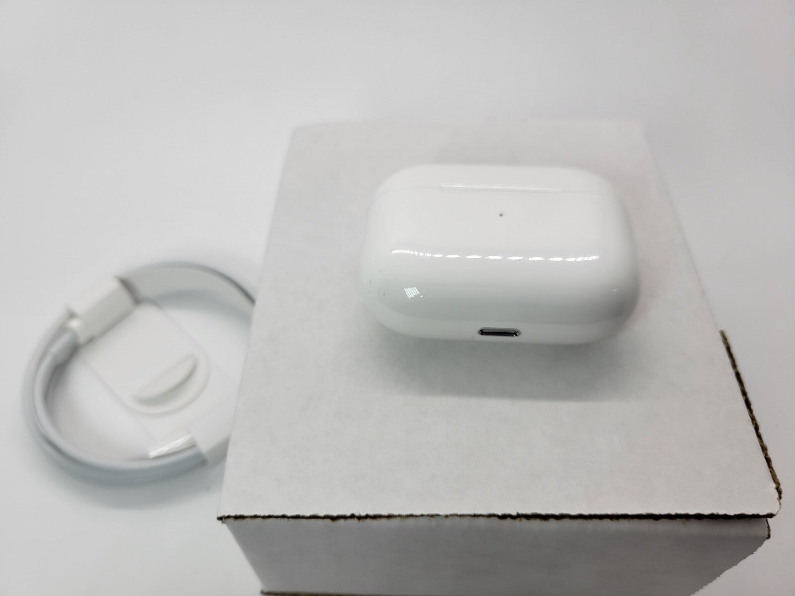 Apple AirPods Pro with wireless charging case and charging cable on white box, very good condition