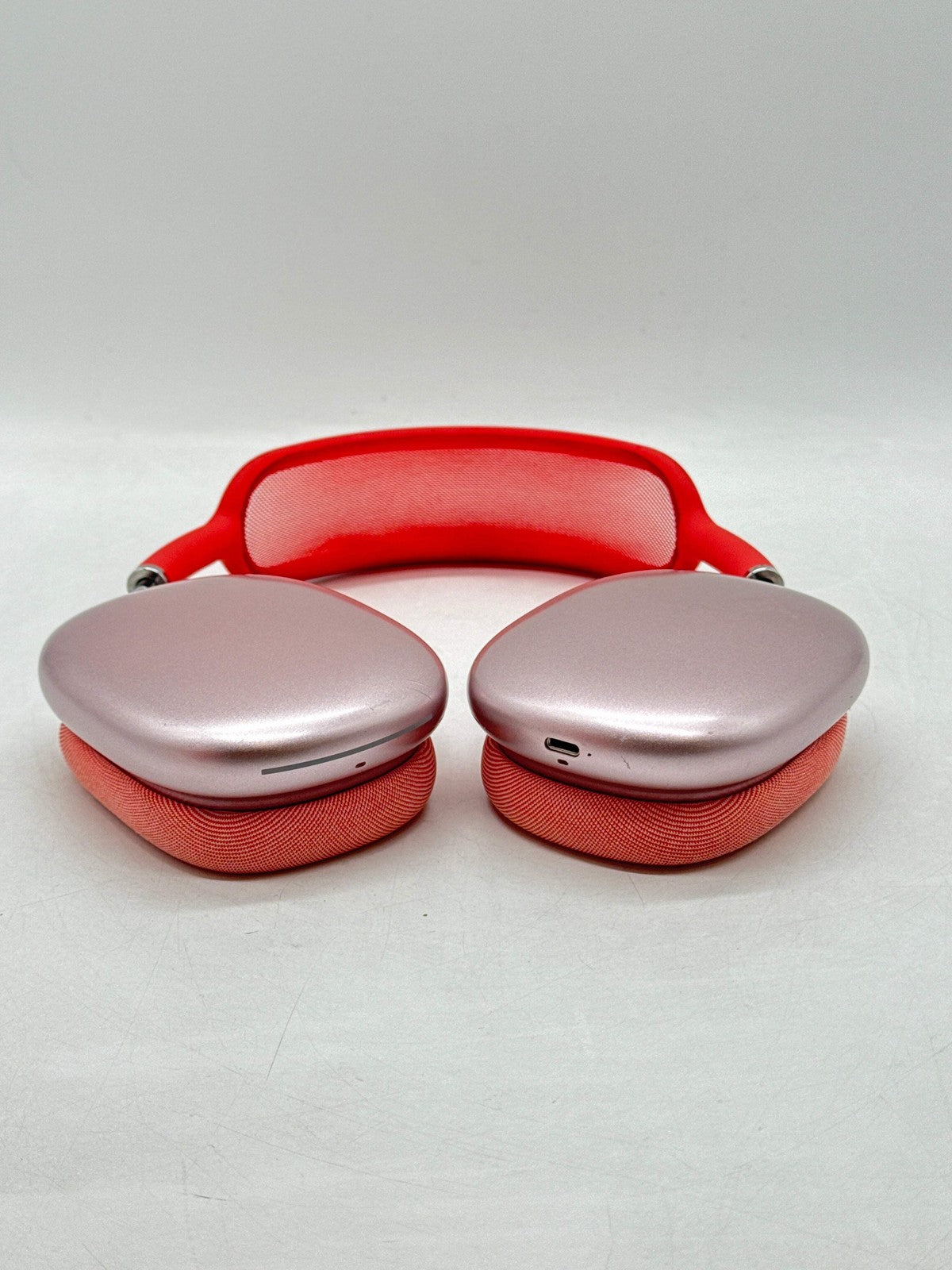 Apple AirPods Max A2096 over-ear headphones in pink with red headband and fabric ear cushions, front view showing charging port