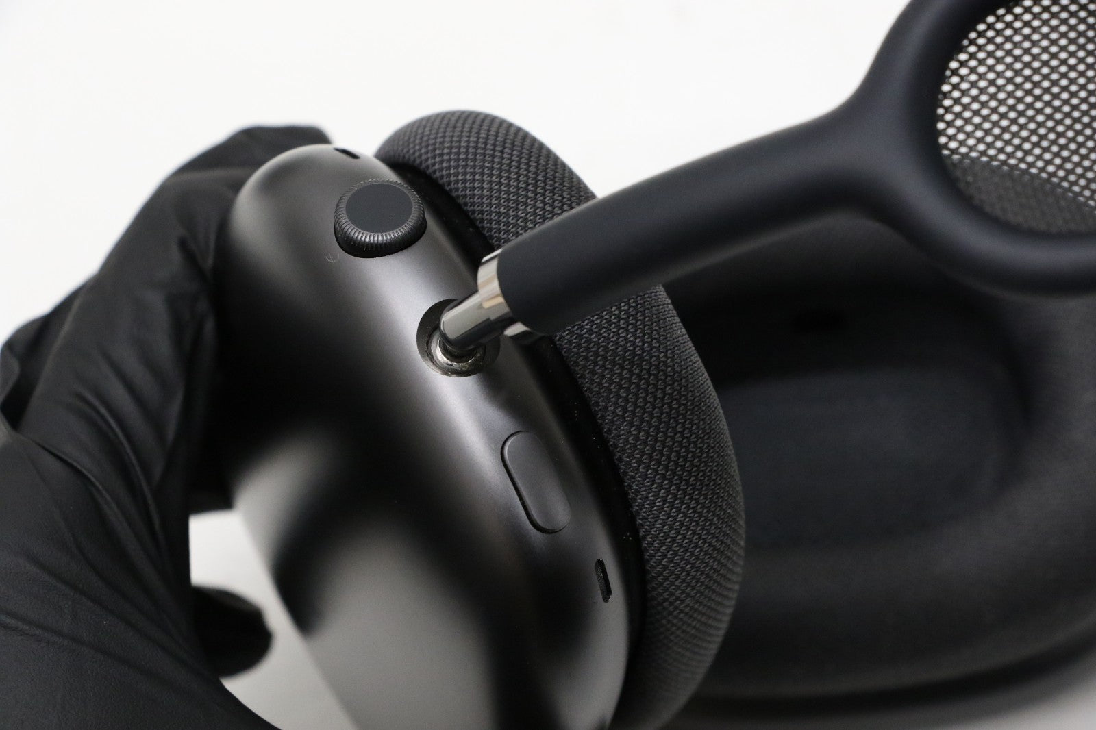 Close-up of Apple AirPods Max Space Gray showing ear cup, digital crown, and mesh headband in hand with black glove