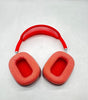 Red Apple AirPods Max over-ear headphones with breathable mesh ear cushions and adjustable headband shown flat on surface