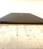 Closed Apple MacBook Pro 15-inch in space gray showing left side with dual Thunderbolt 3 ports and Apple logo on wooden surface