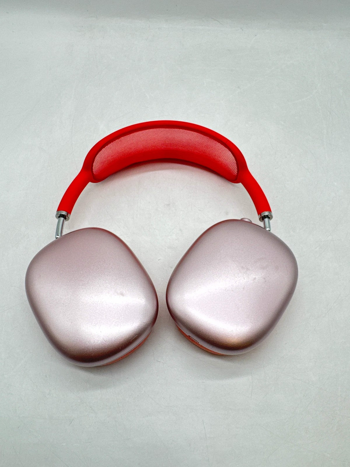 Apple AirPods Max Lightning A2096 over-ear headphones in pink with red headband and silver ear cups shown from top view