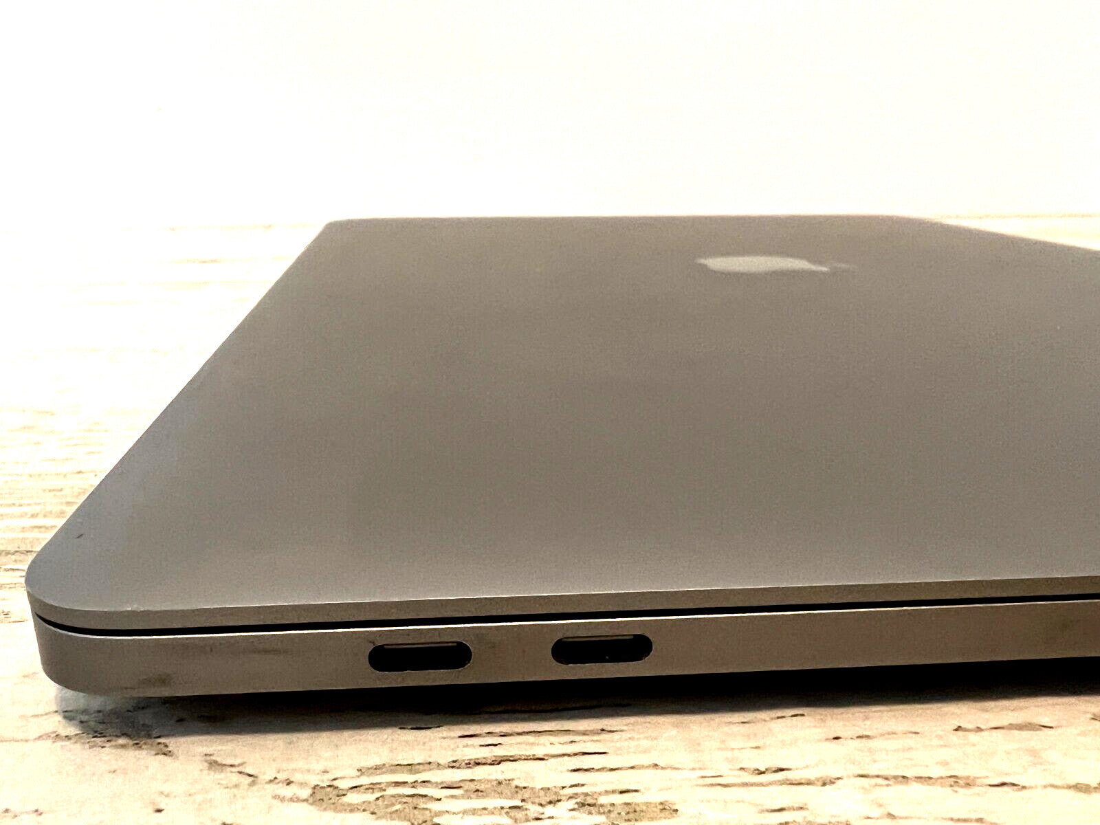 Apple MacBook Pro 15 inch Space Gray closed view showing left side with two Thunderbolt USB-C ports and Apple logo on top