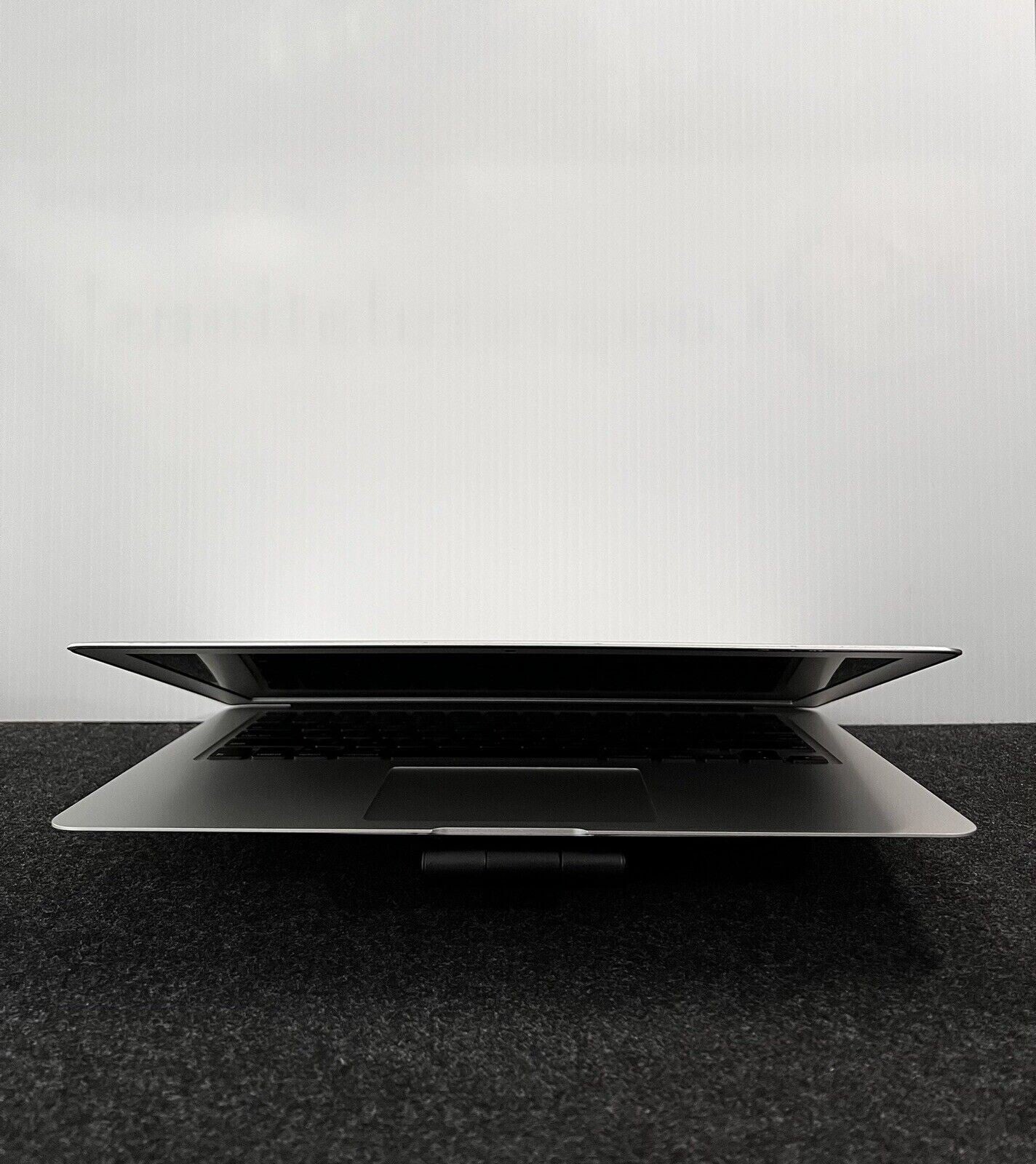 Apple MacBook Air A1466 13.3-inch partially open showing slim design and black keyboard on dark surface