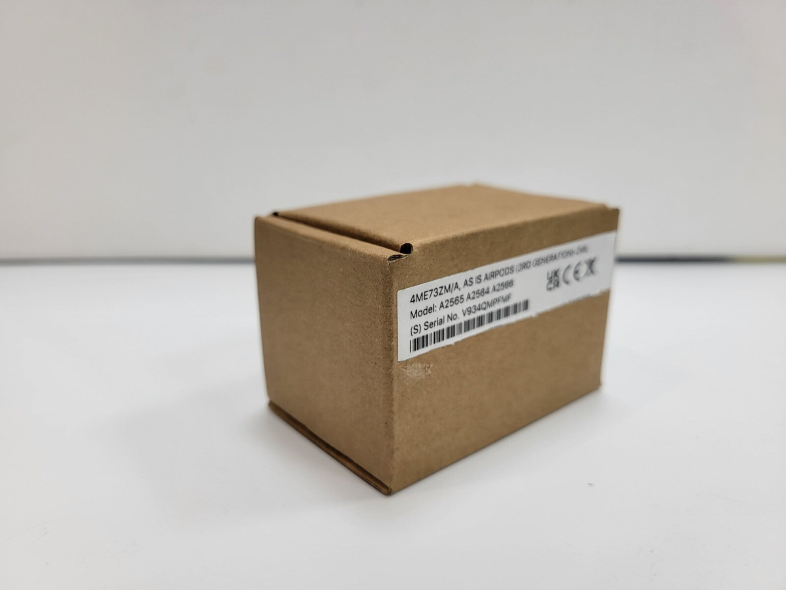 Brown cardboard box with label showing model number and serial details for Apple AirPods 3rd Generation wireless headset