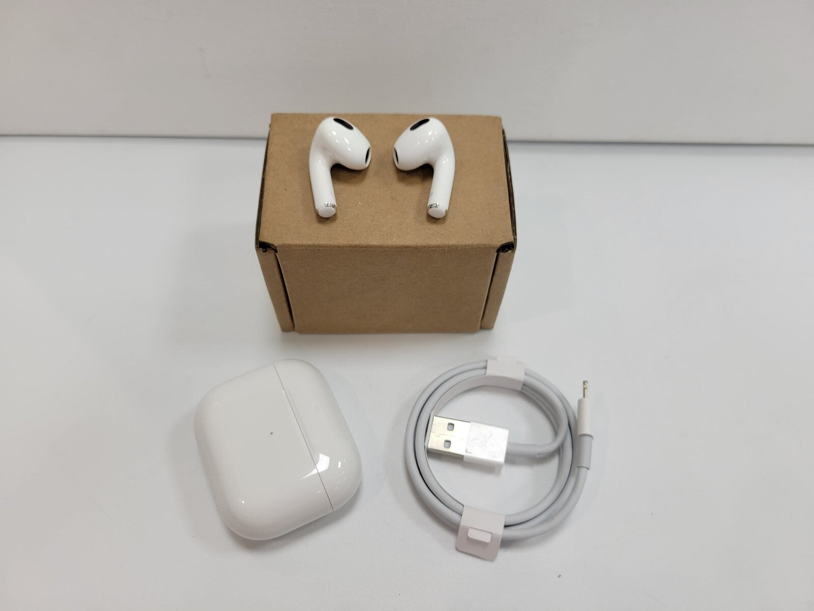 Apple AirPods 3rd Generation wireless earbuds in white with charging case and USB charging cable on white background