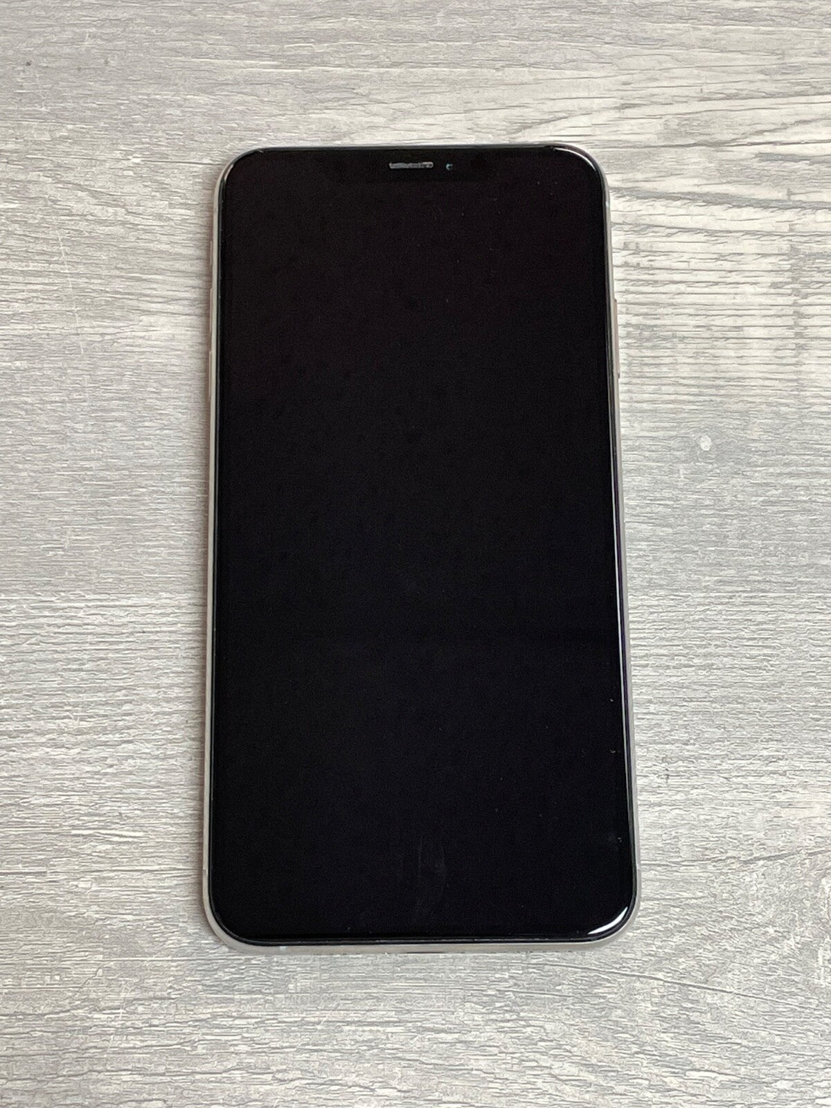 Apple iPhone XS Max with black screen on a wooden surface, model A2101, factory unlocked with dual SIM support.