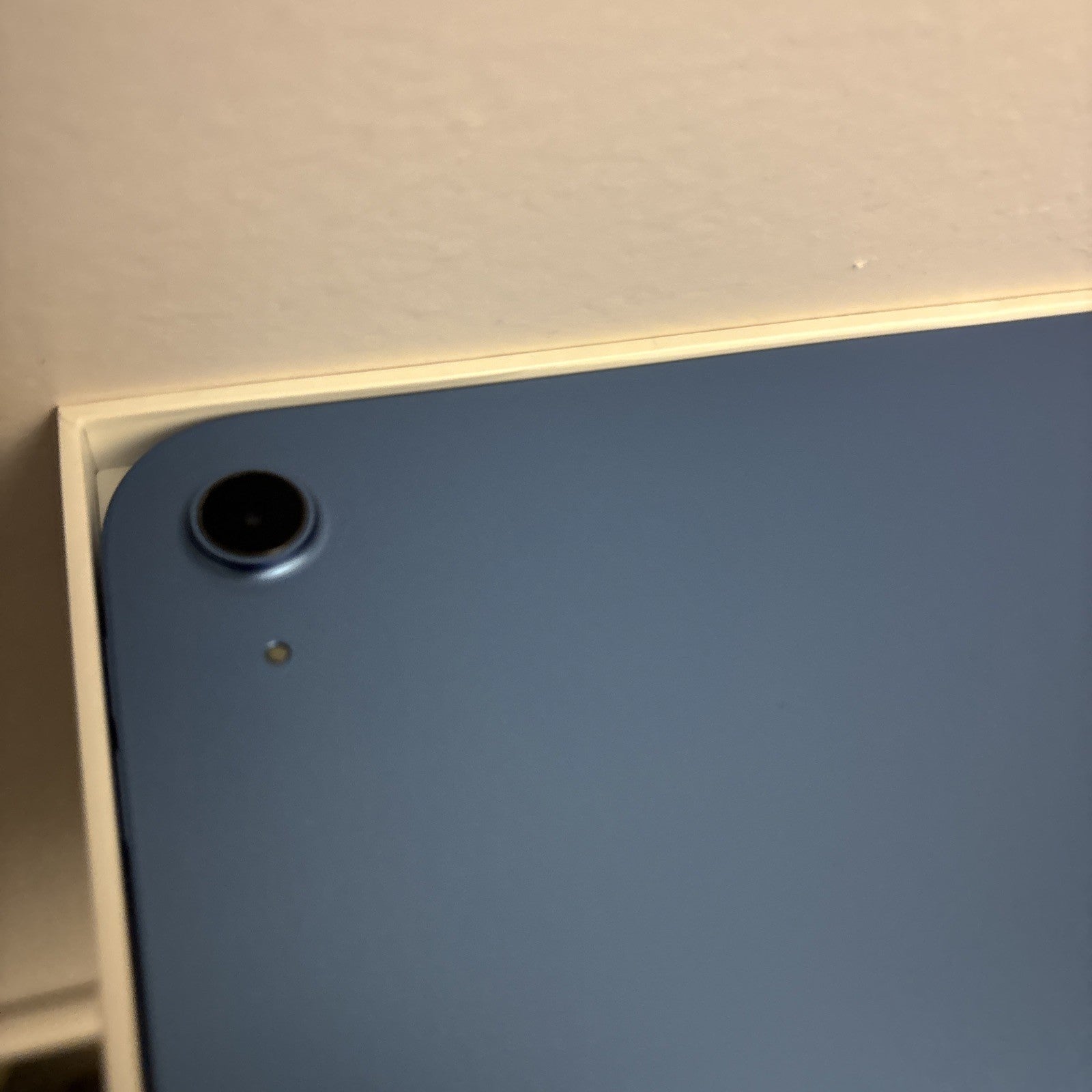 Close-up of blue Apple iPad 10th Gen 10.9-inch rear camera and body in excellent condition on white packaging surface