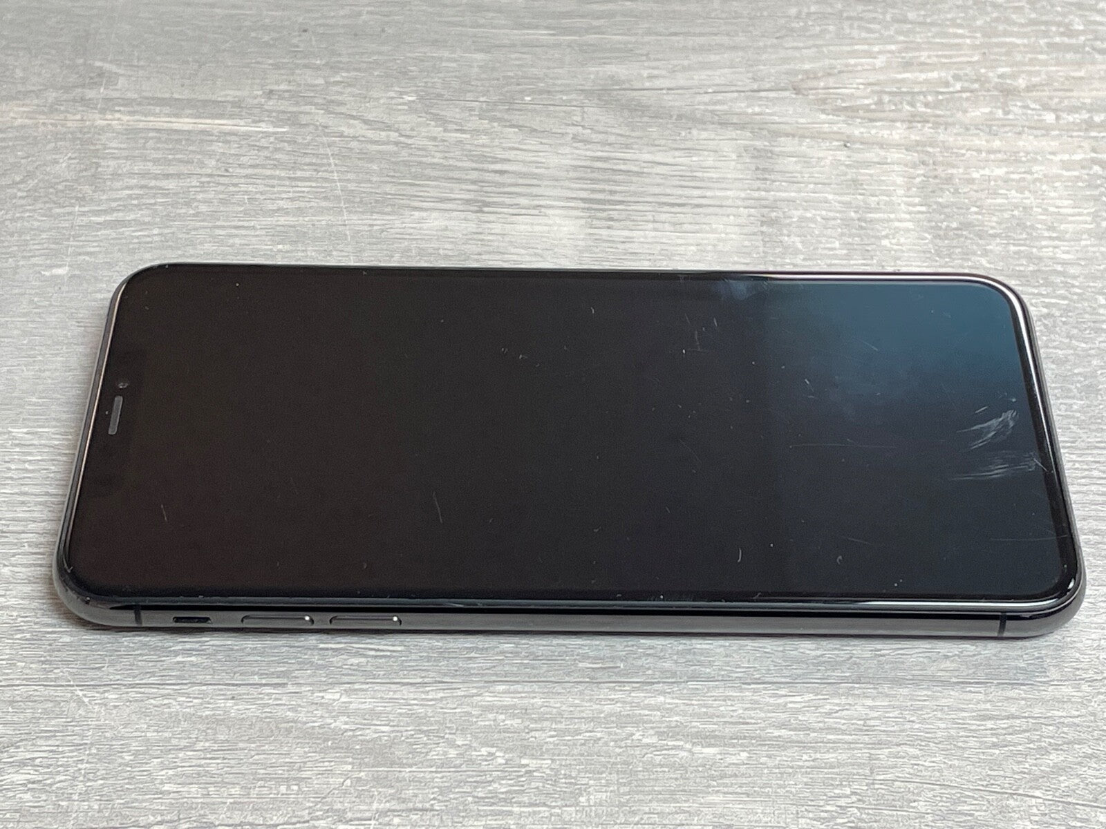 Apple iPhone XS Max with 6.5-inch screen, black front, placed on a light wooden surface, factory unlocked model A2101