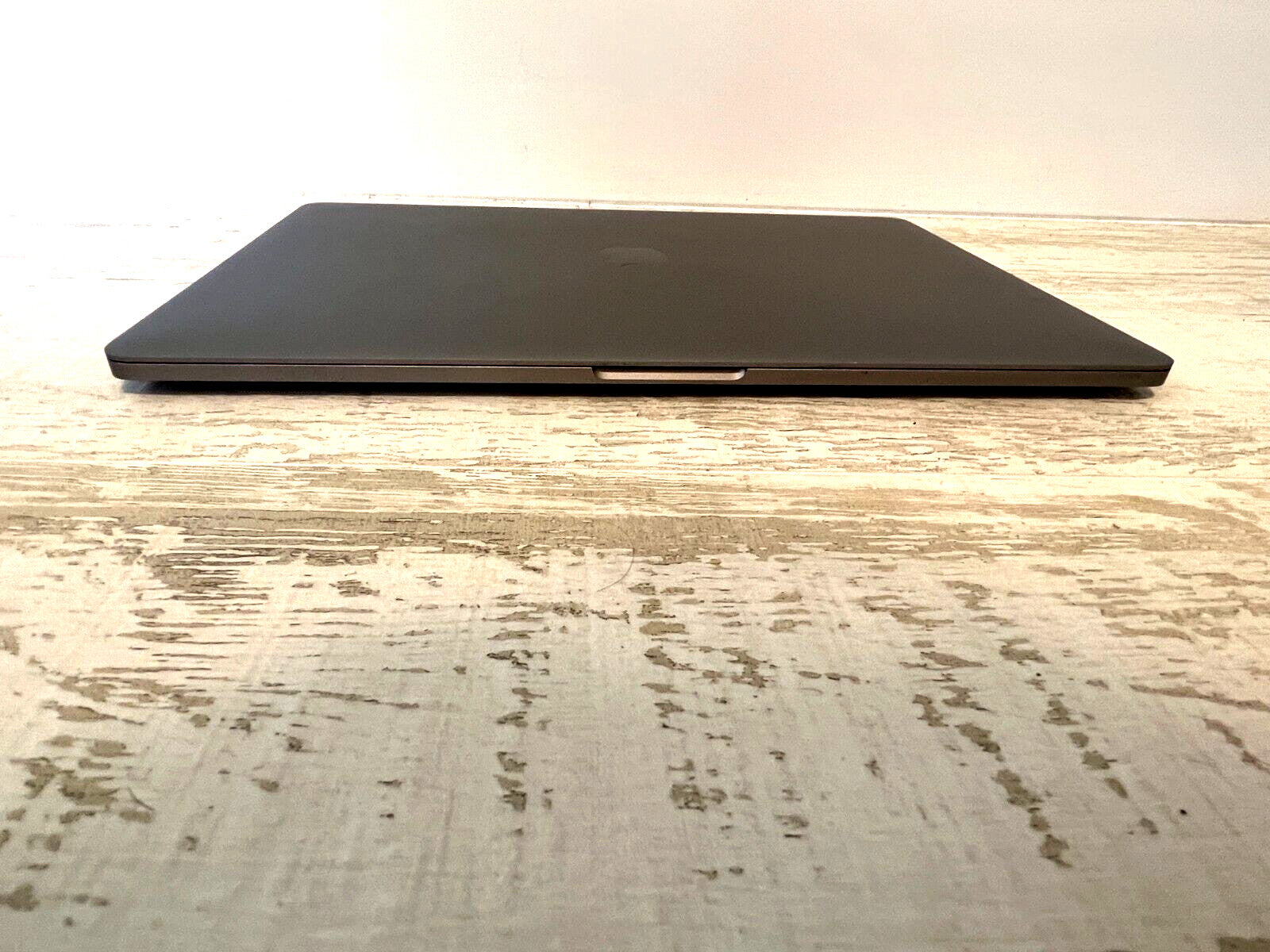 Closed Apple MacBook Pro 15-inch 2018 model in space gray on wooden surface, front view showing edge profile