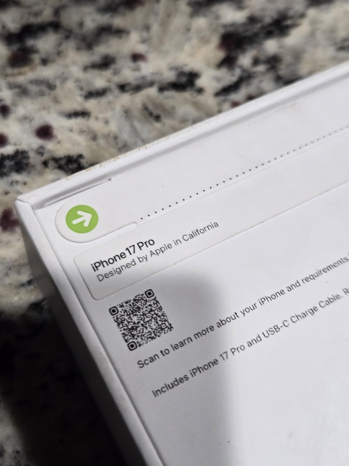 White box packaging corner of Apple iPhone 17 Pro showing label and QR code on granite surface background