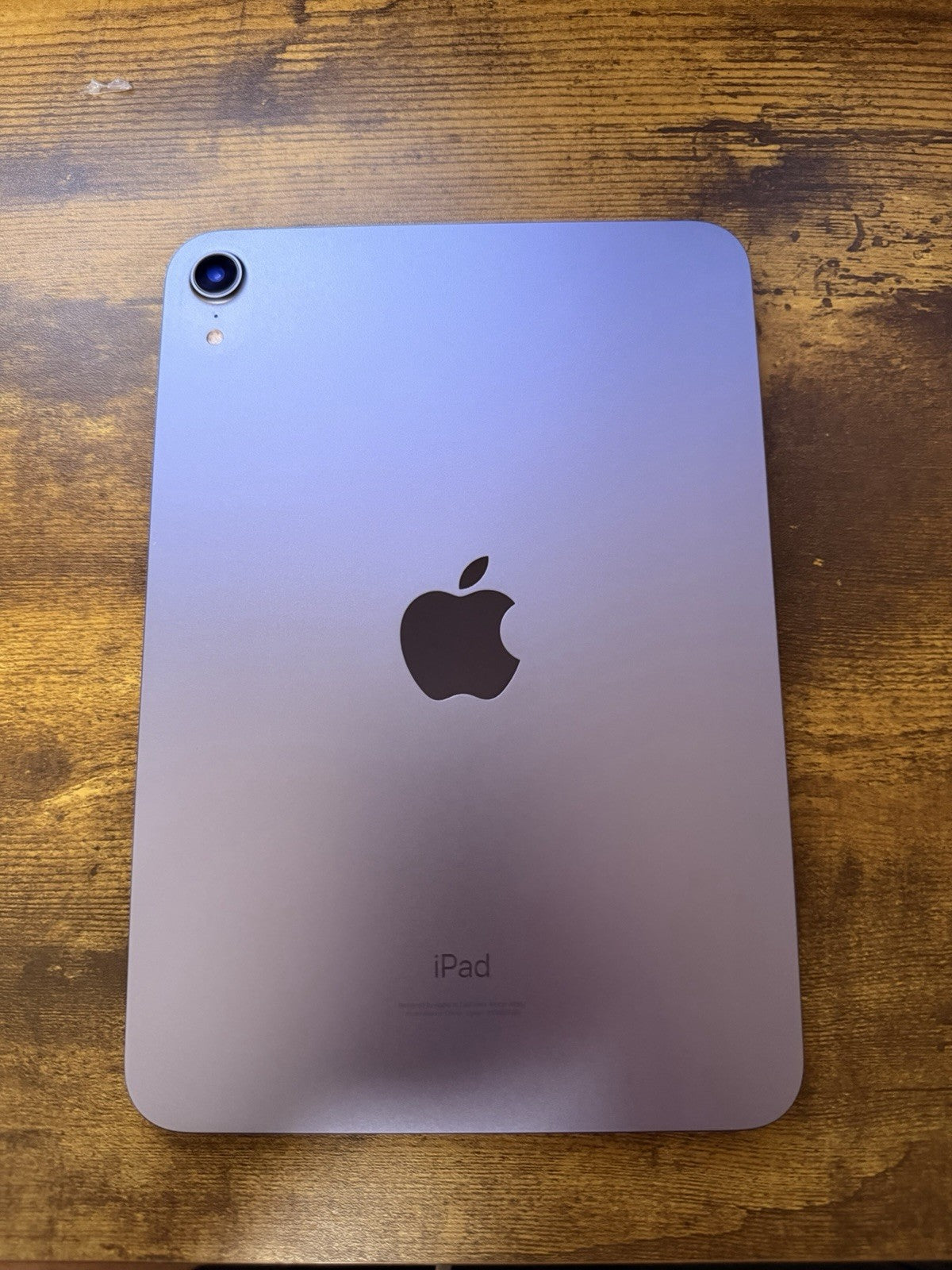 Purple Apple iPad Mini 6th Gen A2567 showing back with single camera and Apple logo on wooden surface